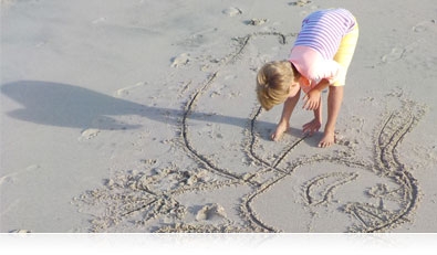 Photo of a boy on the beach, drawing in the sand highlighting scene modes